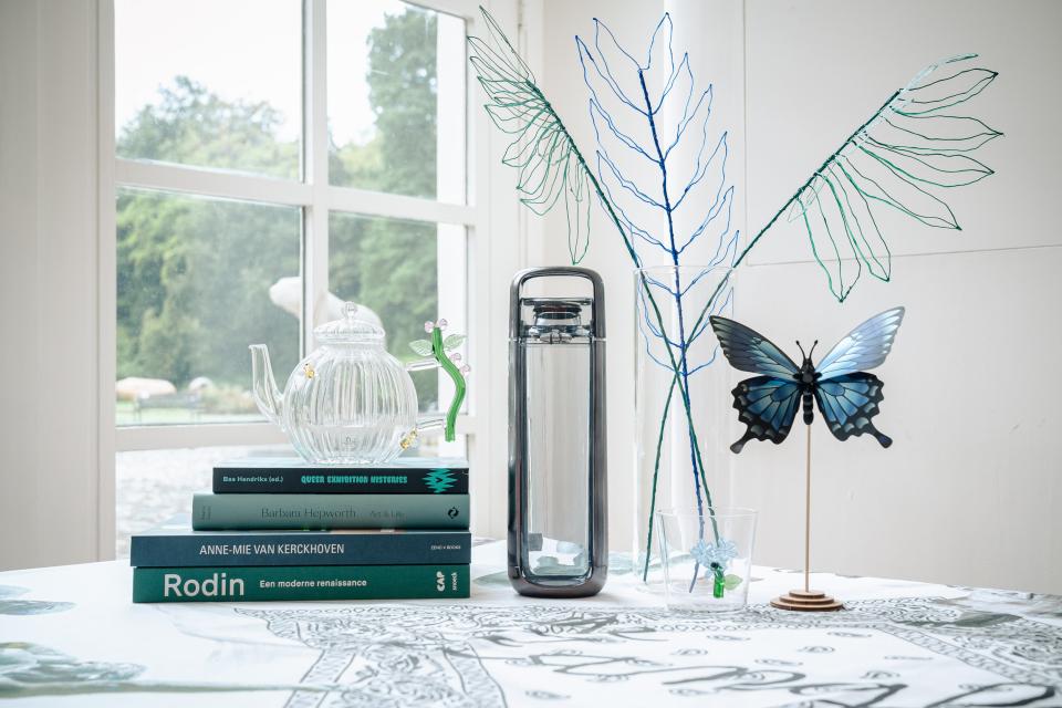 Blauwkleurig assortiment van vier publicaties, glazen theepot, glaasje, waterthermos, bloemen- en vlinderdecoratie