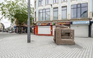 Kruispunt Offerandestraat met Lange Beeldekensstraat met kunstwerk in de vorm van een grote roze granieten rots met courgette, naaimachine en loafer met kwastjes