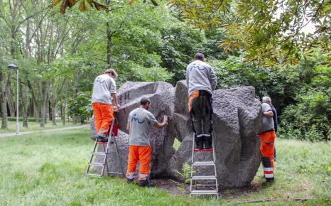 Medewerkers restaureren een werk in het kunstpark 