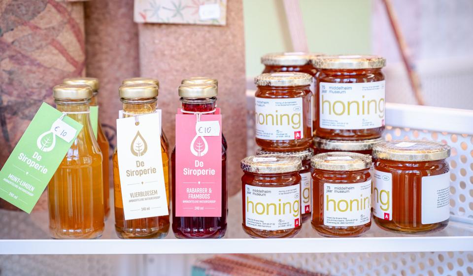 Sfeerbeeld presentatie flesjes siroop en potjes honing in museumshop